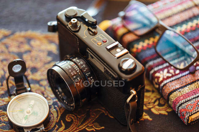 Primer plano de la cámara de fotos vintage arreglada con brújula en la mesa decorativa - foto de stock