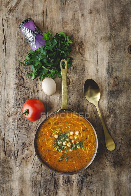 Traditional Harira soup for Ramadan in saucepan on wooden table with ingredients — Stock Photo