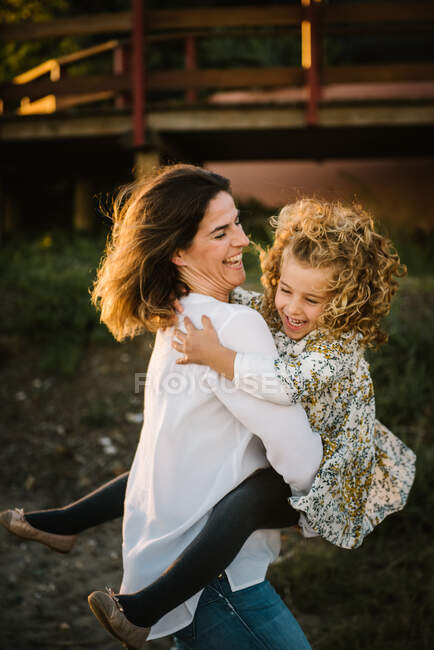 Mulher de meia idade com sua filha na costa do mar sorrindo e abraçando uns aos outros — Fotografia de Stock