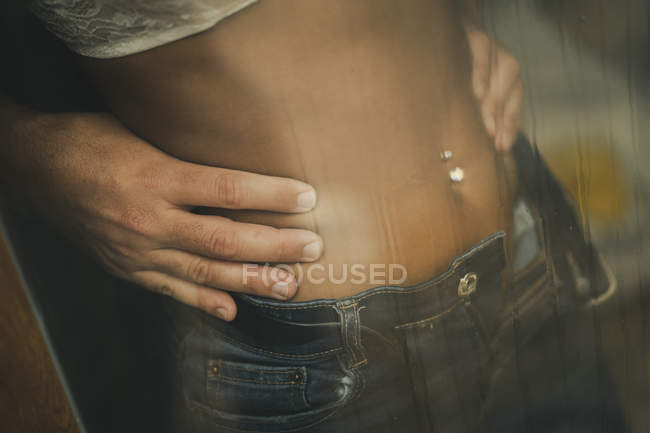 Mãos de homem irreconhecível tocando na cintura da fêmea atrás da janela molhada — Fotografia de Stock