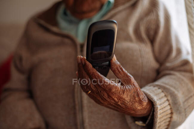 Elderly man using his phone on the interior of his house — Stock Photo