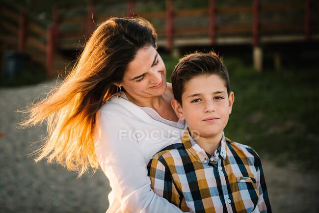 Donna di mezza età con suo figlio sulla riva del mare che sorride e si abbraccia — Foto stock