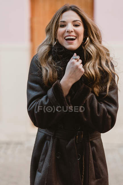 Stylisch lächelnde junge Frau im Vintage-Ledermantel blickt in die Kamera — Stockfoto
