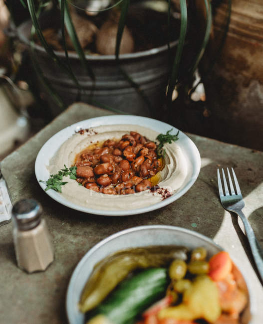 Фасоль и традиционный хумус в тарелке с овощами в горшке на деревянном столе — стоковое фото