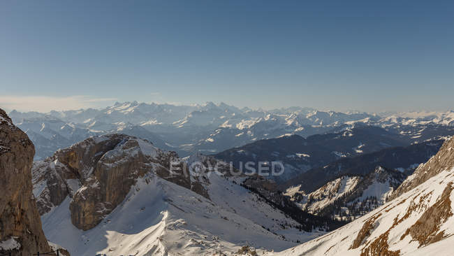 Panoramablick auf den verschneiten Hang vor dem Hintergrund der Berge im Dunst und Sonnenlicht, Schweiz — Stockfoto