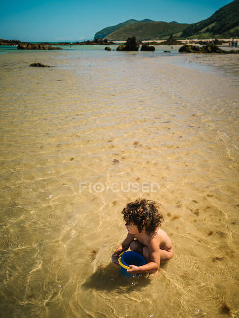 Linda niña construyendo un castillo de arena en la playa - foto de stock