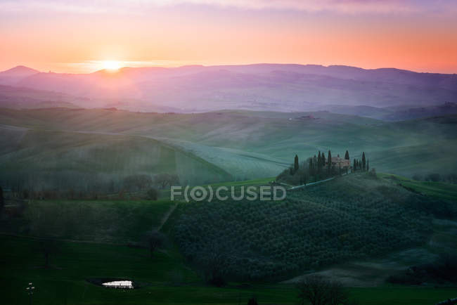 Paesaggio pittoresco di campi verdi con cottage e alberi alla luce del tramonto, Italia — Foto stock