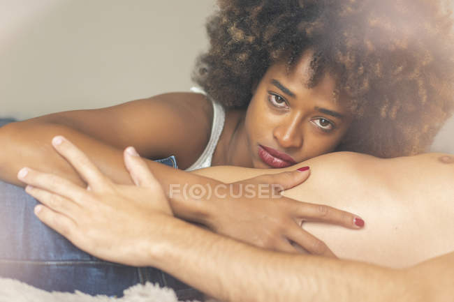 Triste atraente mulher afro-americana abraçando o namorado sem camisa sem rosto enquanto deitado na cama confortável juntos — Fotografia de Stock