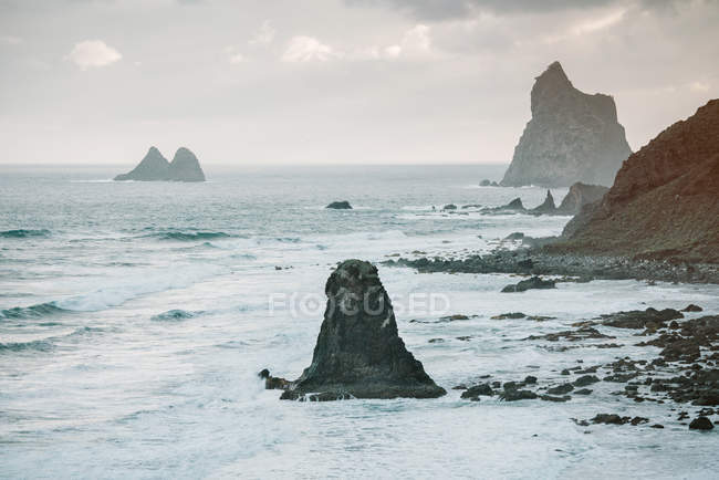 Picturesque view of rocky cliffs in amazing sea on cloudy day in Playa Benijo Tenerife Spain — Stock Photo