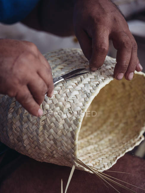 Руки анонимного ремесленника плетут прекрасную корзину из плетеного сушеного пальмового волокна — стоковое фото