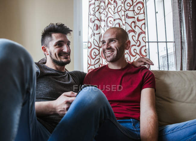 Happy gay couple relaxing on couch at home — Stock Photo