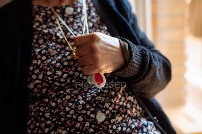 Elderly woman with personal alarm hanging from the neck — Stock Photo