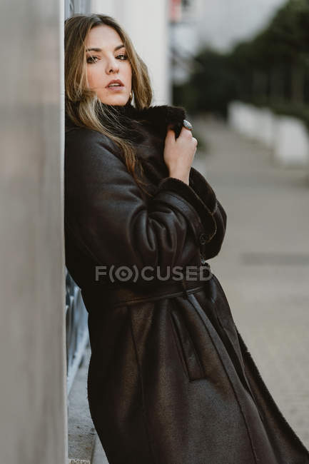 Стильна чуттєва молода жінка спирається на стіну на міській вулиці — стокове фото