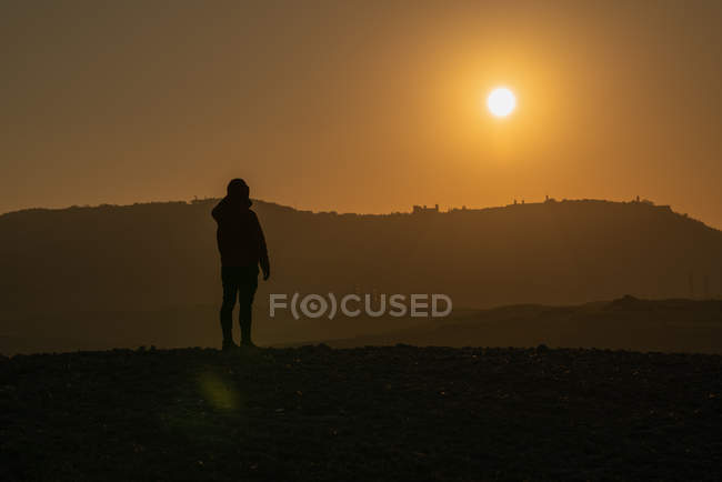 Silhouette einer Person, die auf einem Feld im hellen Hintergrundlicht des Sonnenuntergangs steht, Italien — Stockfoto