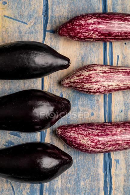 Conjunto de berinjelas roxas e pretas maduras frescas em tampo de madeira desgastado — Fotografia de Stock