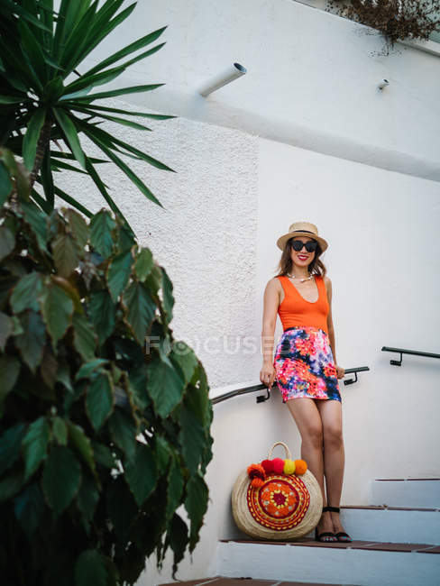 Young classy chinese woman in panama hat and sunglasses sitting at stairs and enjoying a bright summer day — Stock Photo