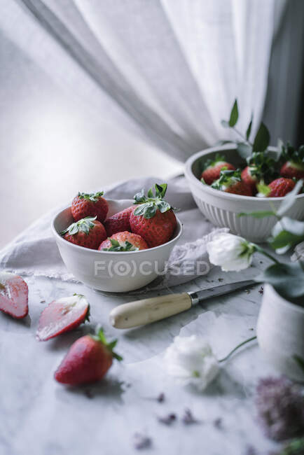 Erdbeeren und Blumen auf Marmortisch — Stockfoto