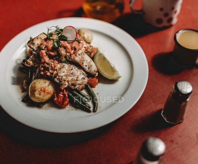Petto di pollo alla griglia e verdure su piatto bianco su sfondo rosso — Foto stock