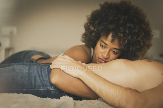Сумно привабливий афроамериканець жінка обіймаючи безликий сорочка хлопця, лежачи на зручному ліжку разом — стокове фото
