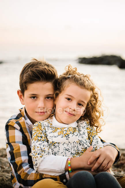 Alegre e bonito menino e menina sorrindo e abraçando uns aos outros na praia — Fotografia de Stock