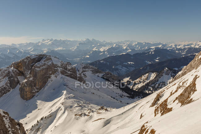 Panoramablick auf den verschneiten Hang vor dem Hintergrund der Berge im Dunst und Sonnenlicht, Schweiz — Stockfoto