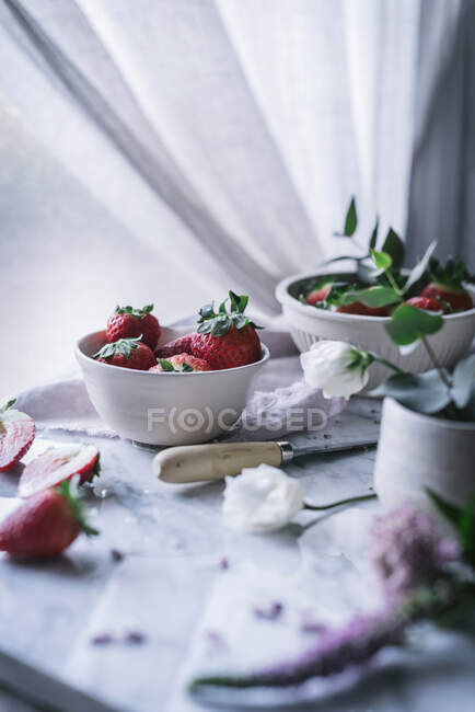 Erdbeeren und Blumen auf Marmortisch — Stockfoto