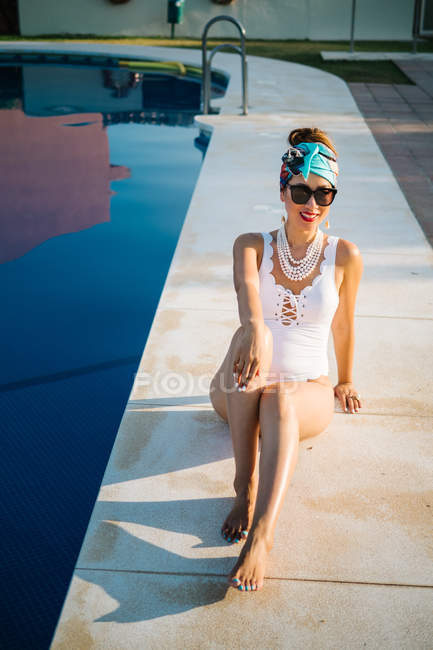 Young rich chinese woman sunbathing by a pool at a luxurious resort — Stock Photo