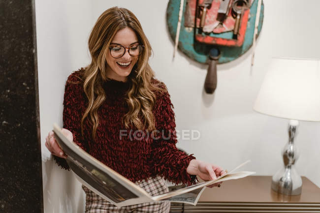 Mujer con estilo leyendo revista y sonriendo - foto de stock