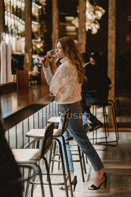 Stilvolle Frau trinkt Wein am Tresen in Bar — Stockfoto
