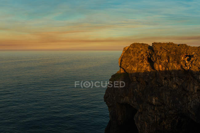 Panoramablick auf riesige felsige Klippen über plätscherndem Wasser gegen den Sonnenuntergangshimmel, Asturien, Spanien — Stockfoto