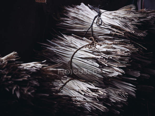 Montones de hojas de palma secas de fibra en taller oscuro - foto de stock