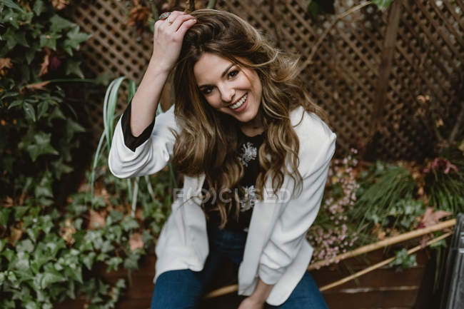 Frau sitzt auf Pflanzkübel im Garten und lächelt — Stockfoto