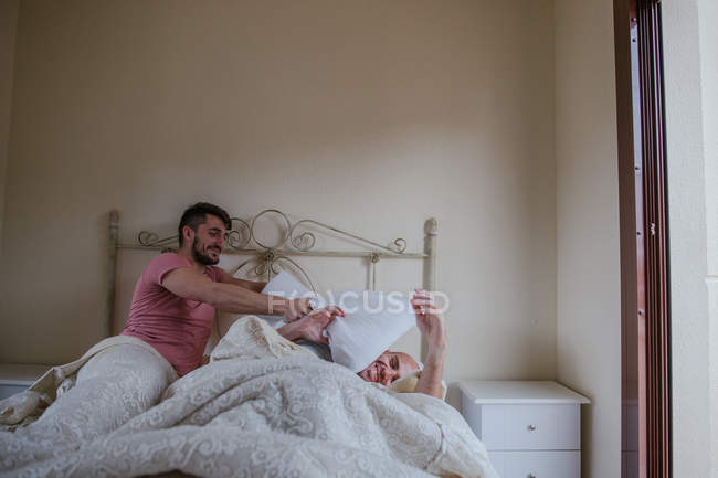 Verspieltes homosexuelles Paar, das morgens im Bett herumalbert — Stockfoto