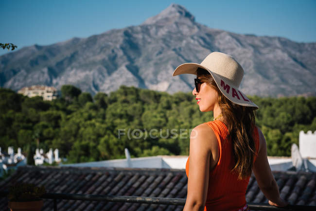 Giovane donna cinese di classe in panama cappello e occhiali da sole godendo di una brillante giornata estiva — Foto stock