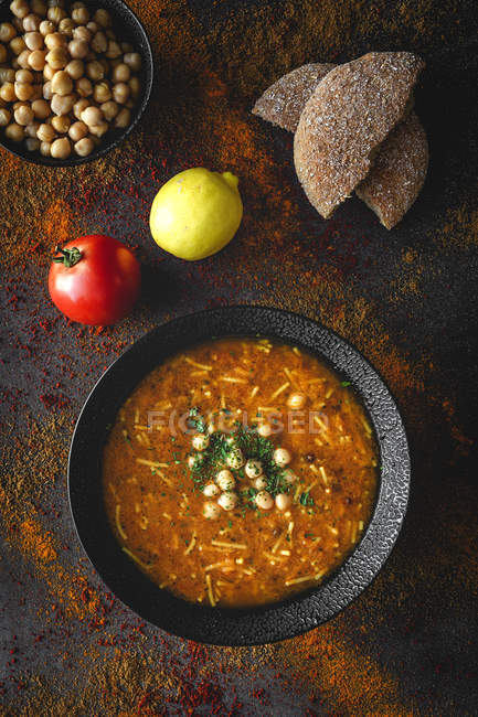 Sopa tradicional de Harira para Ramadã em tigela preta em fundo escuro com ingredientes — Fotografia de Stock