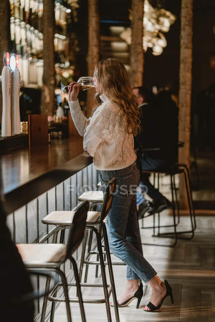 Stylish woman drinking wine at counter in bar — Stock Photo