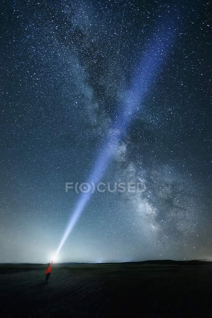 Night sky with majestic Milky way and person with bright upward beam of light — Stock Photo