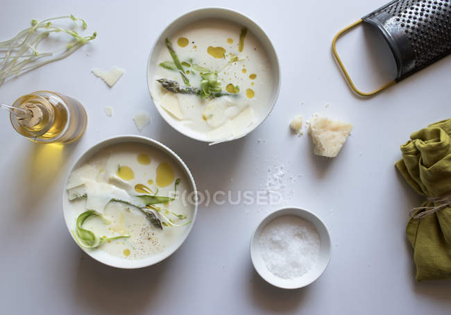 Миски смачного спаржевого вершкового супу з сиром і травами на білому фоні — стокове фото