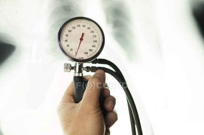 Hand of doctor using medical tonometer in front of blurred x-ray image — Stock Photo