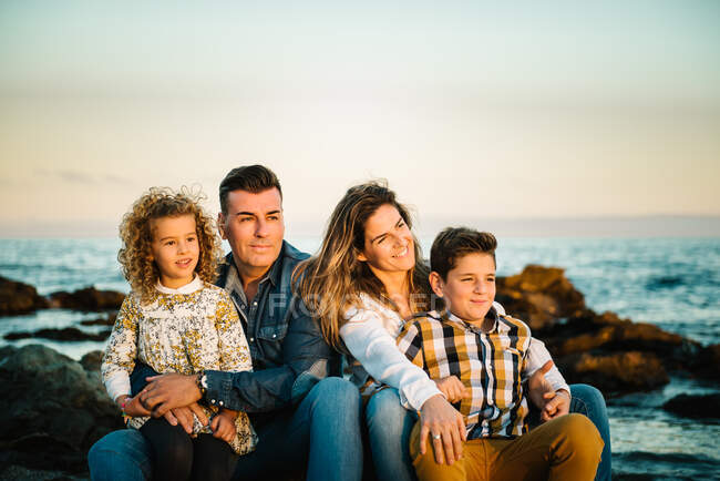 Mann mittleren Alters und Frau mit Kindern an der Küste lächeln und umarmen sich — Stockfoto