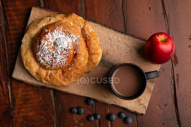 Fresh hot beverage and various tasty breakfast food placed on lumber tabletop in morning — Stock Photo