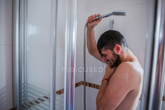 Без сорочки чоловік приймає душ у ванній — стокове фото