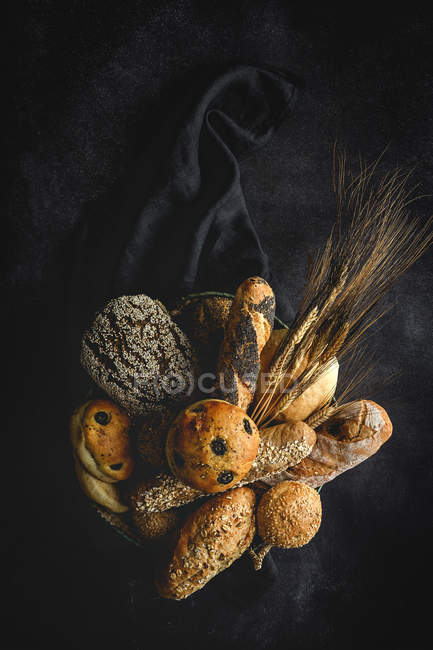 Surtido de panes caseros recién horneados sobre fondo negro - foto de stock