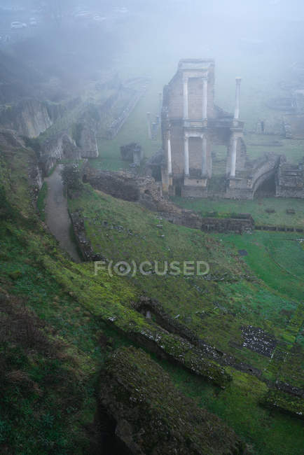 Desde arriba vista de las ruinas verdes musgosas en la niebla pesada, Italia - foto de stock