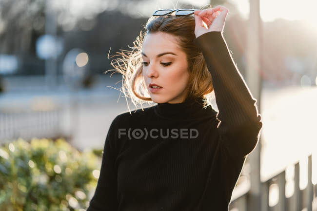Elegante ragazza togliersi gli occhiali da sole sulla strada soleggiata — Foto stock