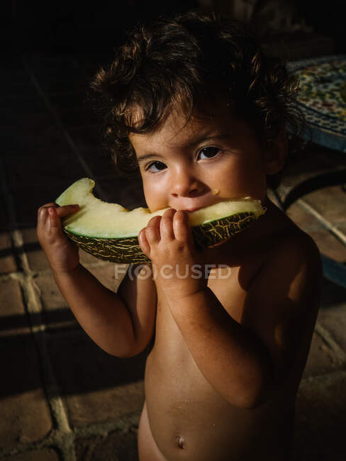 Süßes kleines Mädchen isst Melone draußen bei Sonnenuntergang — Stockfoto