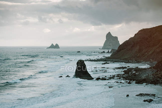 Picturesque view of rocky cliffs in amazing sea on cloudy day in Playa Benijo Tenerife Spain — Stock Photo