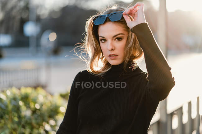 Girl taking off sunglasses on sunny street — Stock Photo