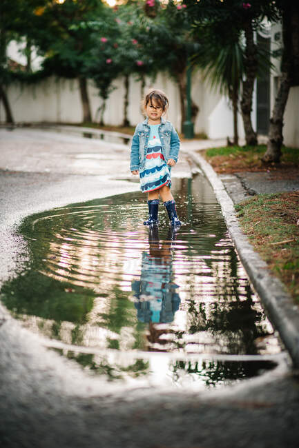 Small girl playing with puddle in street — Stock Photo
