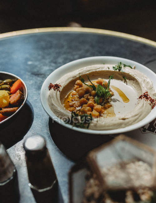 Traditional chickpea hummus in plate on table — Stock Photo